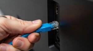 Zbliżenie na dłoń podłączającą kabel Ethernet do telewizora, co jest skutecznym rozwiązaniem problemu zacinania się i buforowania IPTV.